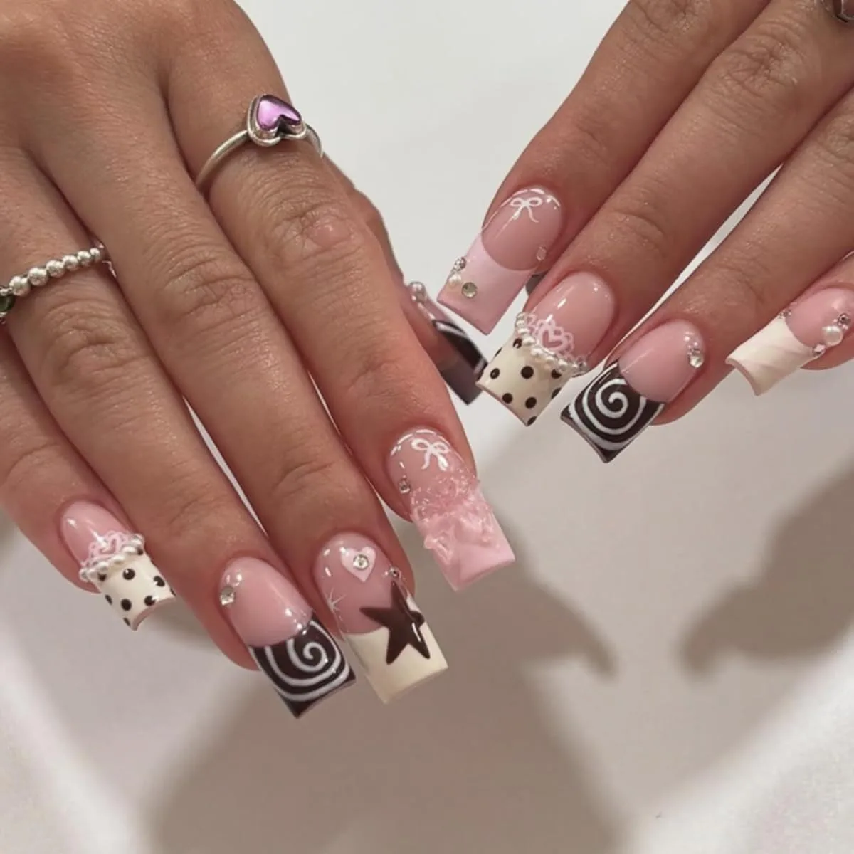 Hands with long square Y2K press-on nails with polka dots, black swirl French tips, star, pearls, lace and bows