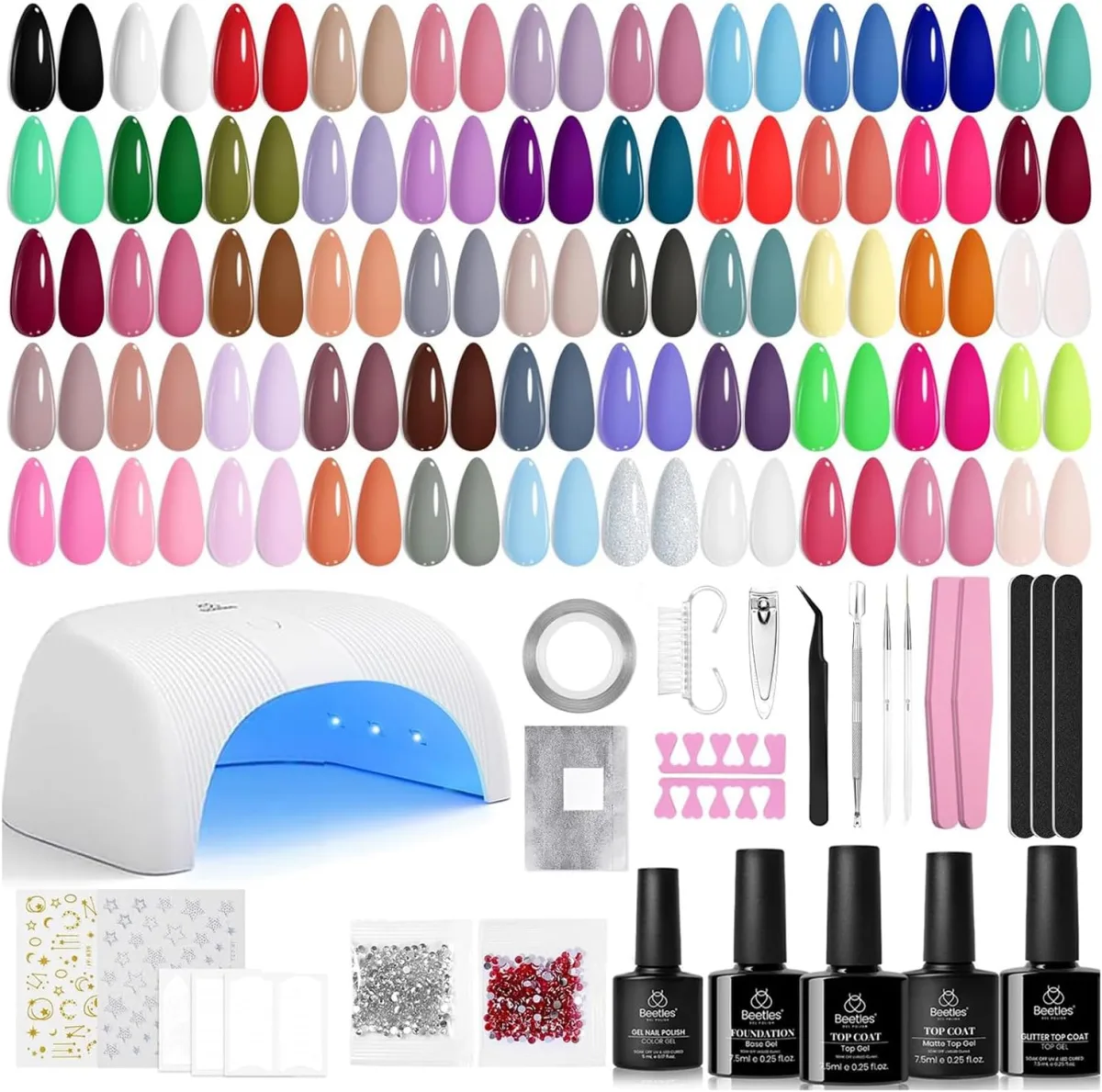 Beetles gel nail kit flat-lay with paired colour swatch tips, a white UV LED lamp, tools and five black system bottles
