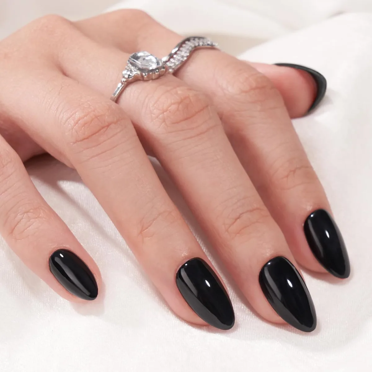Hand with long almond nails in solid glossy black polish, wearing a large stone ring
