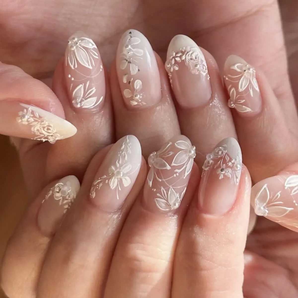 Long almond press on nails with white lace florals and tiny rhinestones on nude pink
