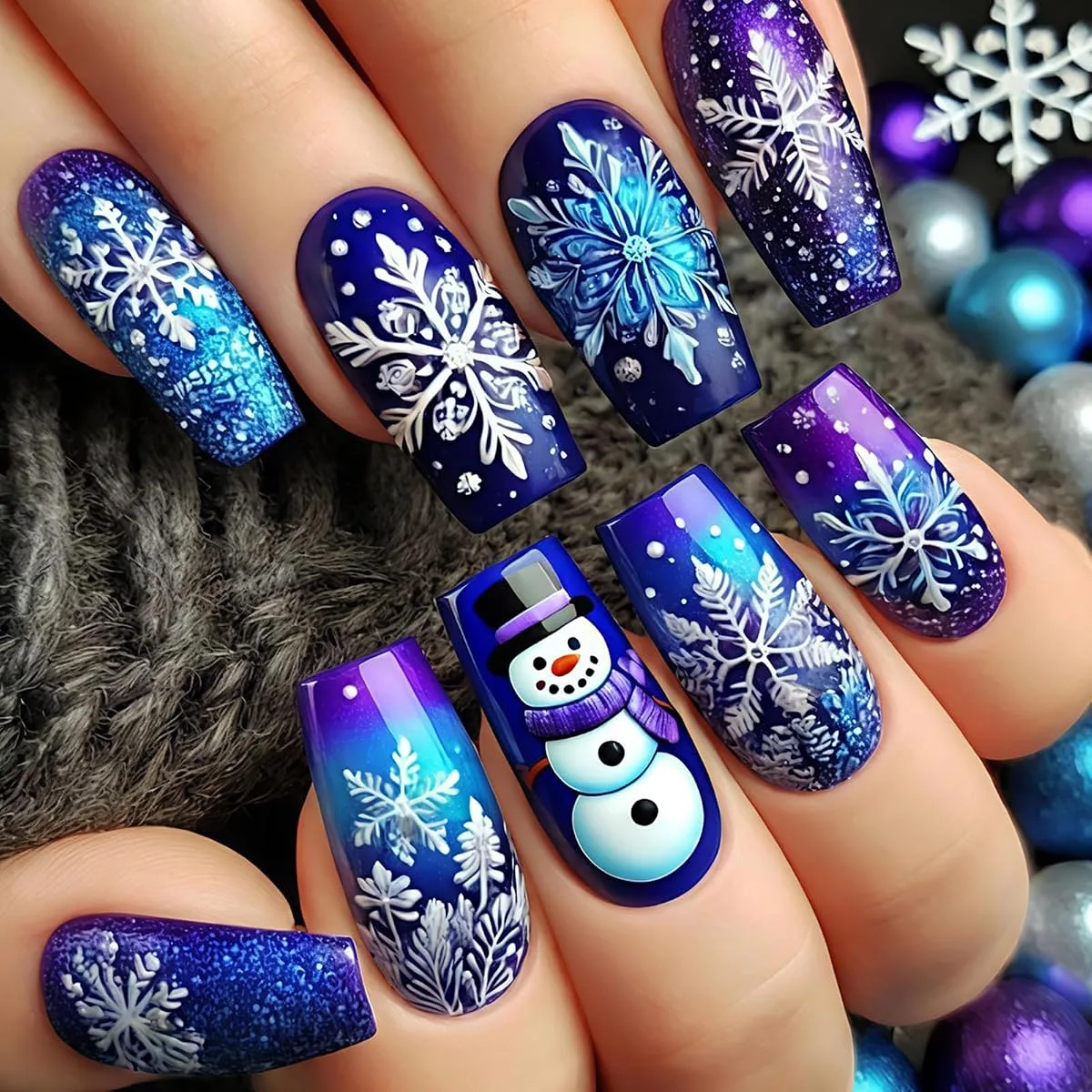 Long coffin nails in royal blue, purple and turquoise with white snowflakes, glitter and one snowman nail