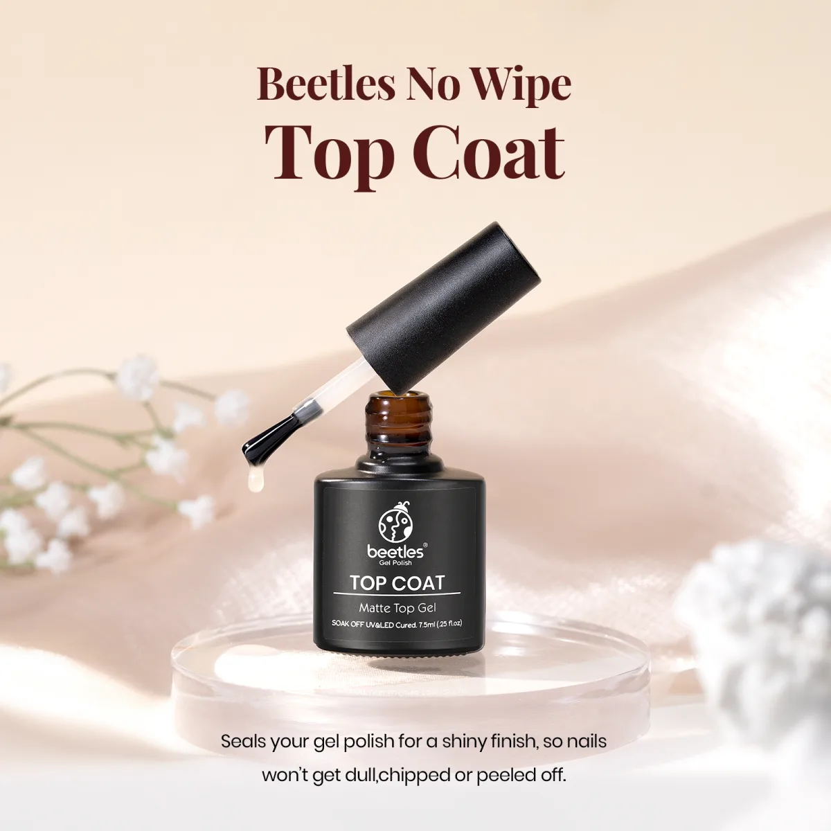 Beetles No Wipe matte top coat bottle with applicator brush on a beige silk backdrop