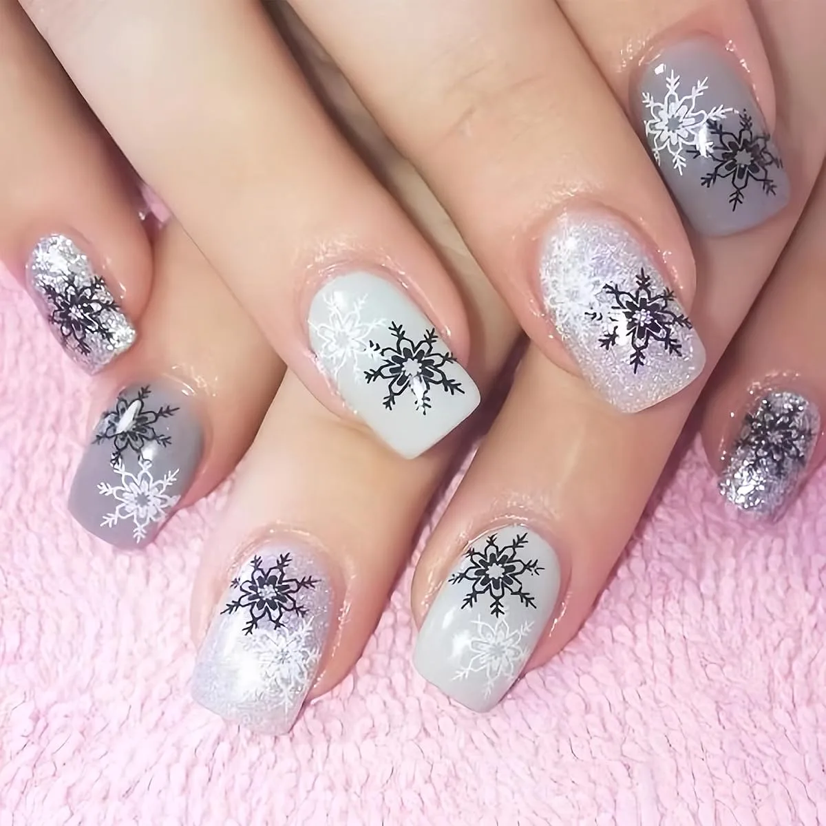 Short square acrylic false nails in grey white and silver glitter with black and white snowflakes