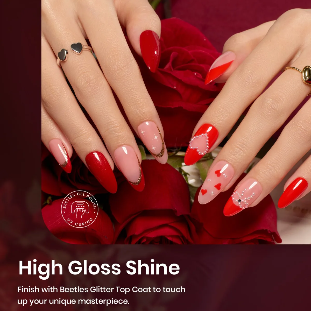 Two hands with long almond red and nude nails with pearl hearts and gold glitter French